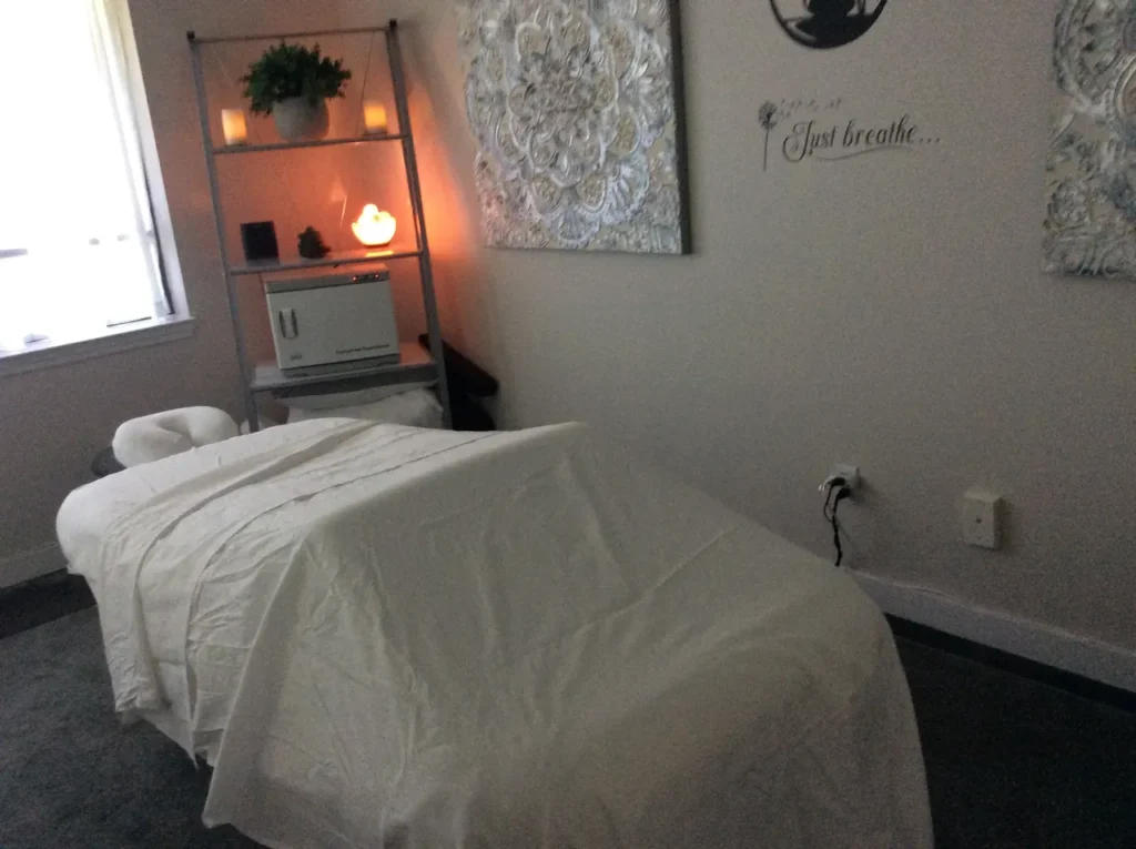 A person in comfortable workout clothes doing gentle arm circles outdoors in a peaceful garden setting, with morning sunlight filtering through trees in the background.